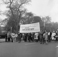 March against Vietnam War: Workers Party, Shoot ID: 408, Negative: 9. Image of a black and white photograph. In the photograph, a crowd stands in the middle of a tree-lined street. The photograph includes a poster that says "Psychologists-Psychotherapists Against War in Vietnam". Full text includes "Psychologists-Psychotherapists Against War in Vietnam".