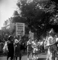 Labor Day, Shoot ID: 406, Negative 30. Image of a black and white photograph. In the photograph, a group of women with matching hats and posters walk down a street. Several women carry US flags. In the background, there are several trees and the top of a large building.  The photograph includes a poster that says "Protect Human Rights as well as Property Rights" (part of the poster's text is covered). Full text includes "Protect Human Rights as well as Property Rights". 
