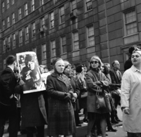 Demonstration against Vietnam War: Union Groups, Shoot ID: 409, Negative: 14. Image of a black and white photograph. In the photograph, a crowd stands in front of a large building. Several people in the crowd carry posters and flags. 