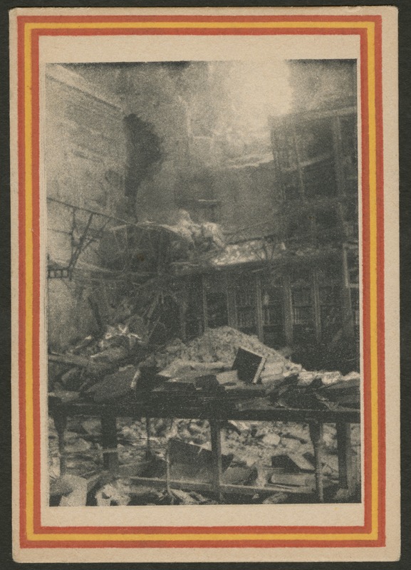 Front of postcard (recto). Image of a photograph of a room or building in ruins. The space contains tall bookshelves, books, and rubble. In the background, there are ruins of a balcony or mezzanine-like structure. The photograph has a red and yellow striped border. 